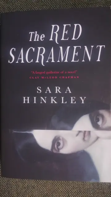 The Red Sacrament by Sara Hinkley, with a Victorian era portrait, side on, and split down the middle to give a disturbing perspective