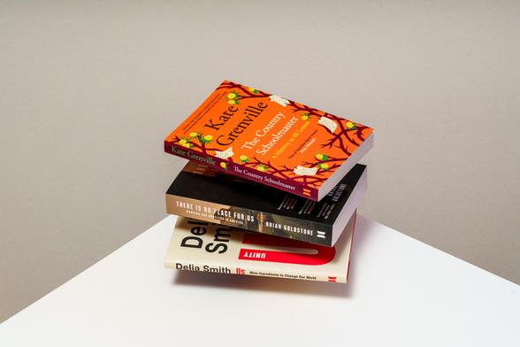 The three books photographed in a pile, slightly floating above each other, on a plain background