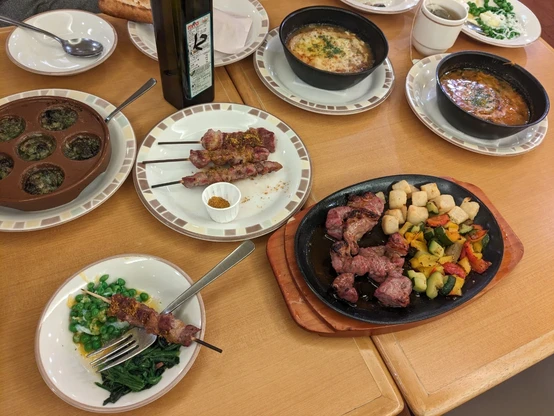 サイゼリアの机。エスカルゴ、アロスティチーニ、玉ねぎのズッパ、ミネストローネ、柔らか青豆のサラダ、ラムと野菜のグリルなど