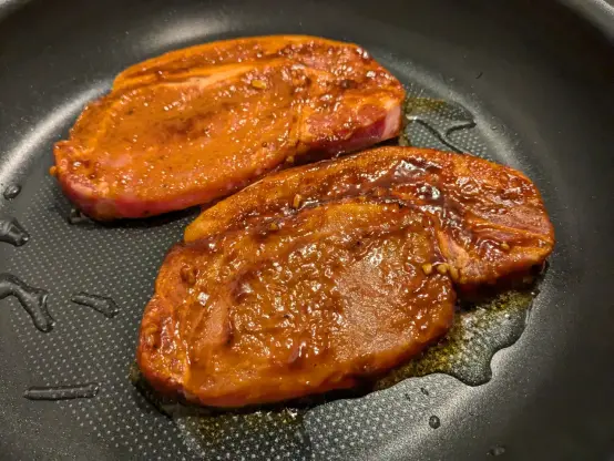 フライパンで焼かれる豚肉2切れ